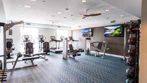 A gym with exercise equipment, a television, and a patterned floor.