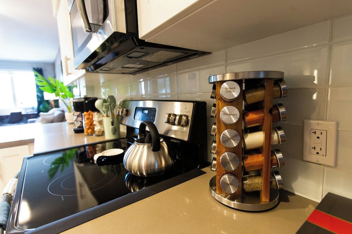 Well-stocked kitchen counter with a stove, kettle and spice rack