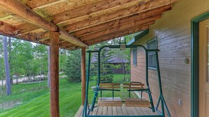 Eine überdachte Veranda mit Schaukel und Bank, Holzterrasse und Blick auf eine grüne Landschaft.