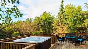 Une terrasse en bois avec un jacuzzi et du mobilier d’extérieur.