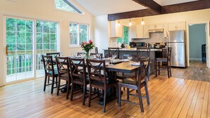 Une cuisine spacieuse dotée d’un plancher en bois, de grandes fenêtres et d’appareils électroménagers modernes.