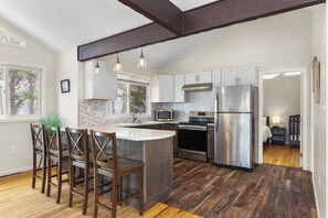 Una cocina moderna con una isla central, electrodomésticos de acero inoxidable y suelo de madera.