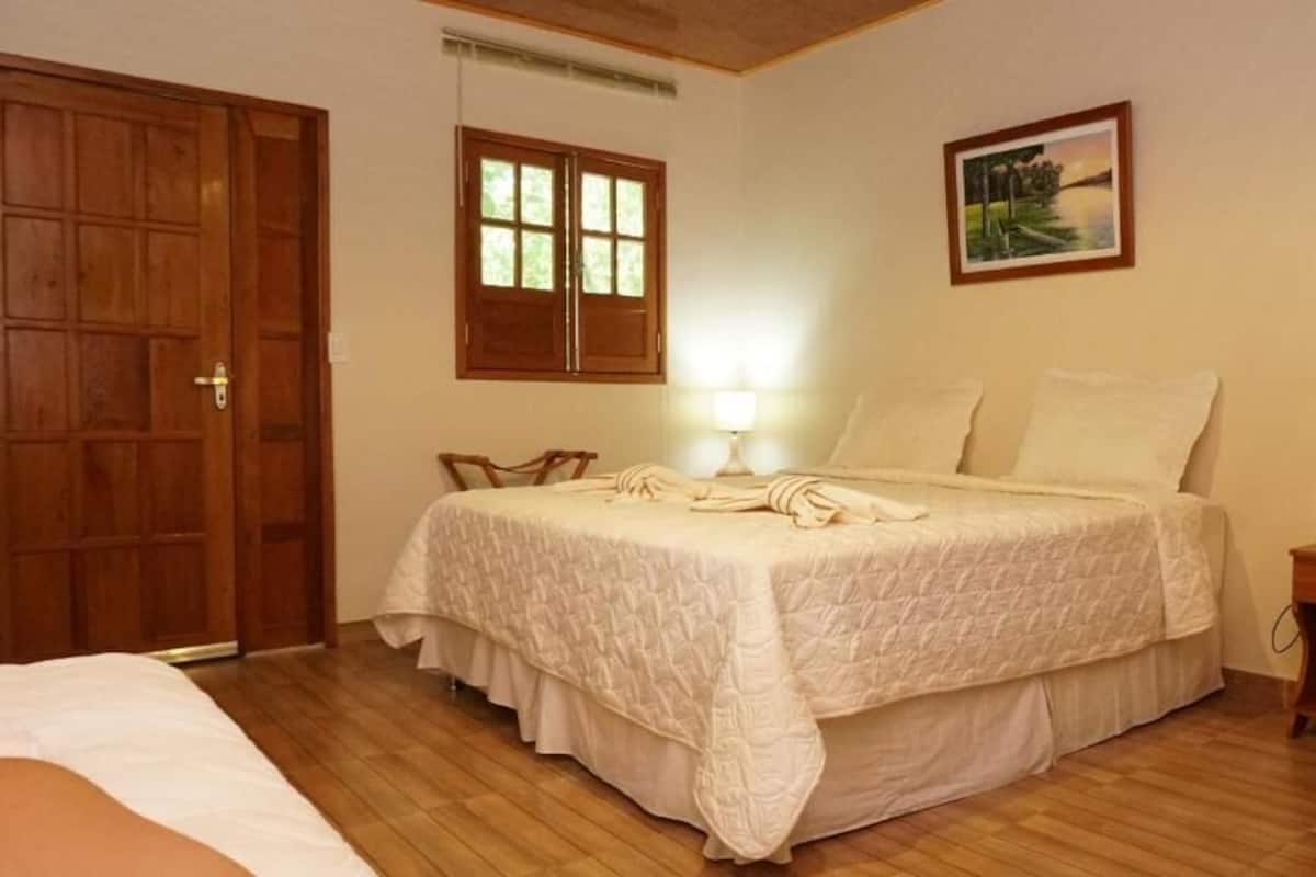 A bedroom with a bed, a wooden wardrobe, a nightstand, and a window.