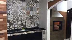 Cozinha com ladrilhos estampados, bancada preta e parede de tijolos.