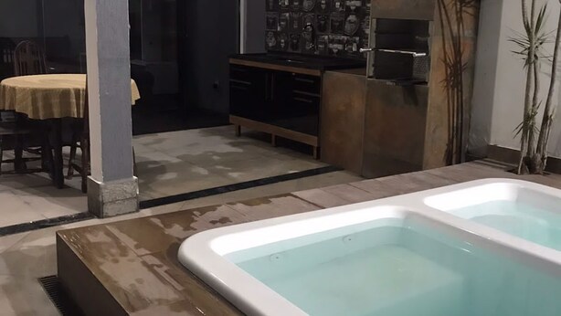 Uma área de spa com hidromassagem, deck de madeira e um espaço de refeições com mesa e cadeiras.