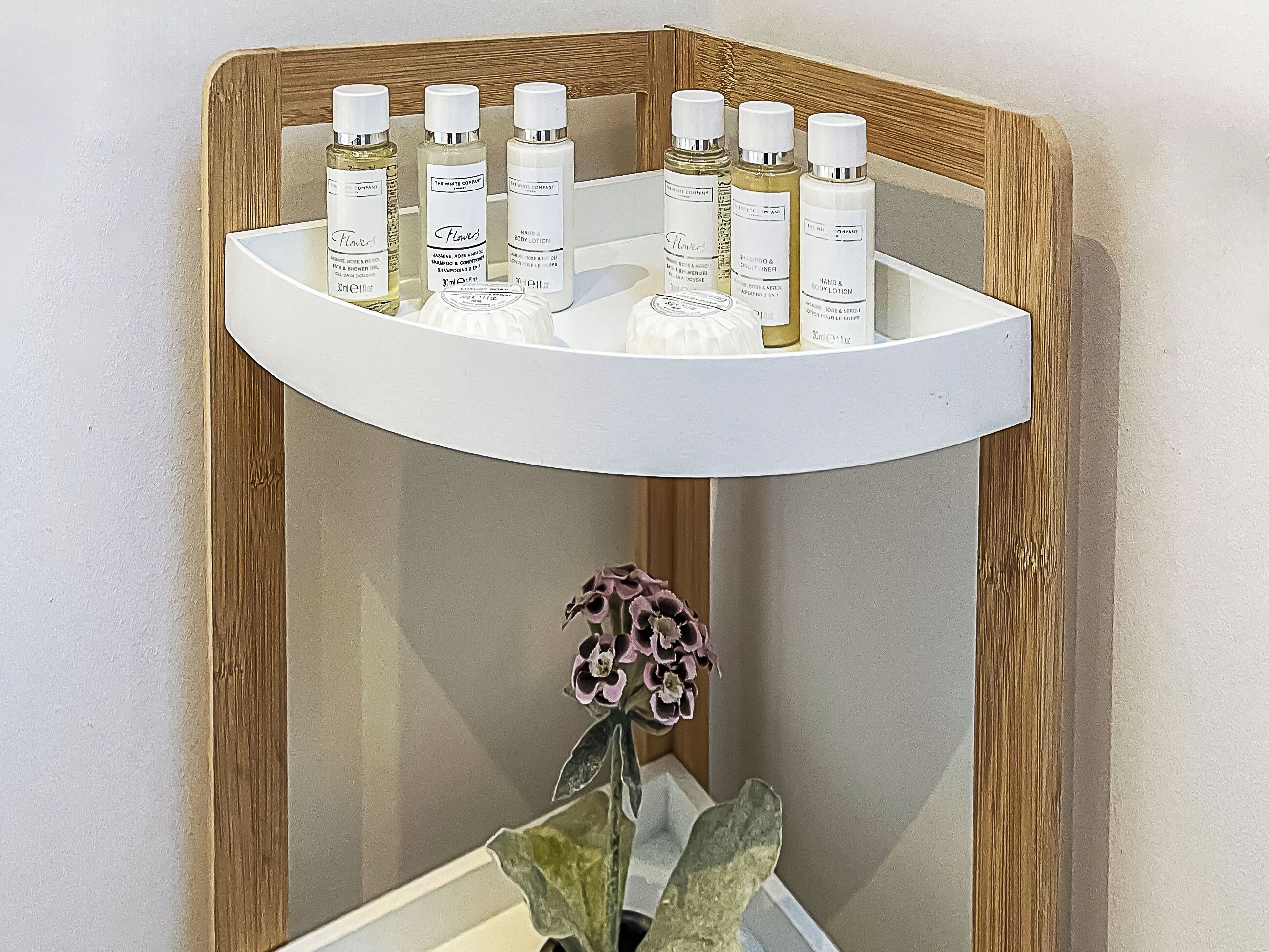 A shelf with various toiletries and a vase with flowers.