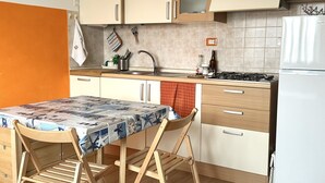 A compact kitchen with a table, chairs, a sink, a stove, and cabinets. - M221 - Marcelli, new two-room apartment 100mt from the sea (Marcelli)