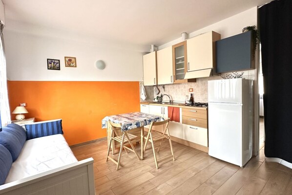 A compact living space with a kitchenette, a dining area with a table and chairs, and a bed.