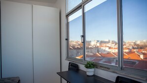 A balcony with a table, chairs, a potted plant, and a view of a cityscape. - Just4uApartment 2 - Near Lisbon & Beach - With AC (Almada)