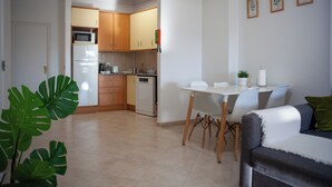 A modern kitchen with wooden cabinets, a white refrigerator, and a dining area with a white table and chairs. - Just4uApartment 2 - Near Lisbon & Beach - With AC (Almada)