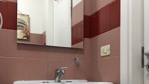 A bathroom with a white sink, a mirror, and a red trash bin.