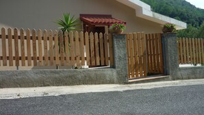 A modern building with a sloped roof, a wooden picket fence, and two potted plants.