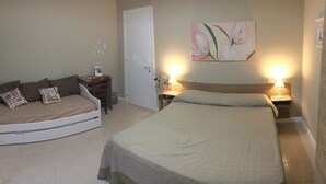 A bedroom with a bed, a chair, a desk, and a door.