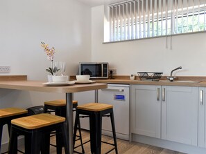 A modern kitchen with a wooden countertop, bar stools, a microwave, a sink, and a window with blinds. - 1 bedroom accommodation in Herne Common, near Herne Bay (Herne Common, near Herne Bay)