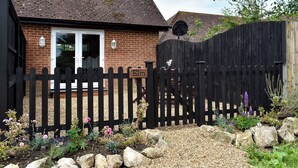 A brick house with a black picket fence, a white door, and a window.