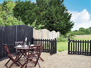 An outdoor seating area with wooden chairs and a table, surrounded by a wooden fence and a gravel path. - 1 bedroom accommodation in Herne Common, near Herne Bay (Herne Common, near Herne Bay)