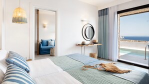 Habitación de hotel con cama, mesita de noche, espejo, vista al mar y balcón.