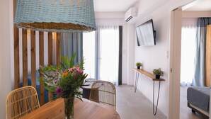 Un moderno comedor con una mesa de madera, sillas de mimbre, un florero con flores, una lámpara colgante y un televisor montado en la pared.