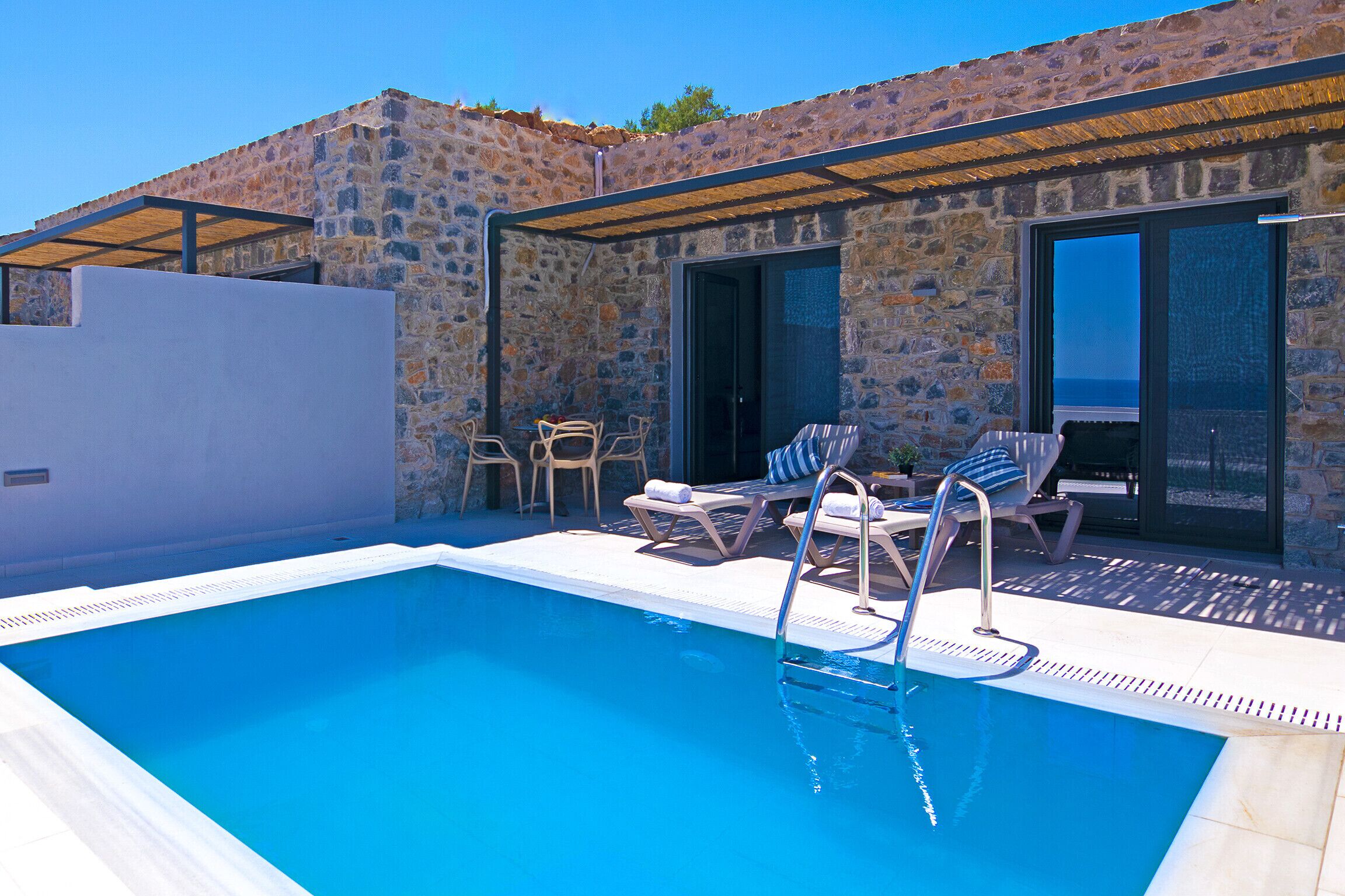Una piscina con un muro de piedra y un área de estar cubierta.