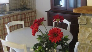 Una cucina con tavolo e sedie, una lampada a sospensione, una finestra vista e un muro in pietra.