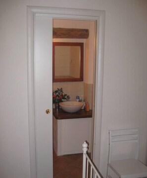 A bathroom with a white door, a white sink, a mirror, and a white radiator.