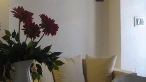 Un soggiorno con un divano bianco, una poltrona beige e un vaso bianco con fiori rossi.