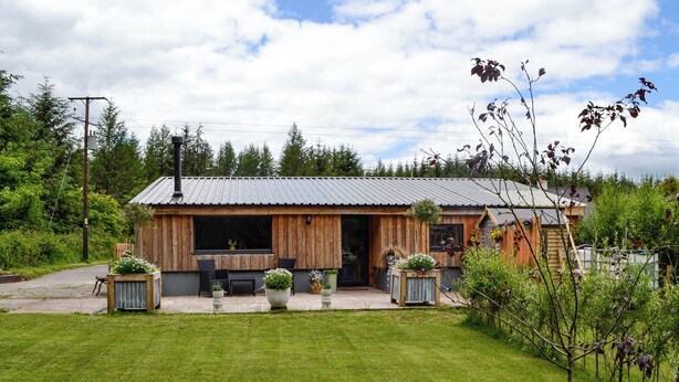 A rustic wooden cabin with a metal roof, a patio with outdoor furniture, and a well-maintained lawn. - 2 bedroom accommodation in near Trecastle, Brecon (near Trecastle, Brecon)