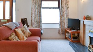 Una sala de estar con sofá, televisión y chimenea.