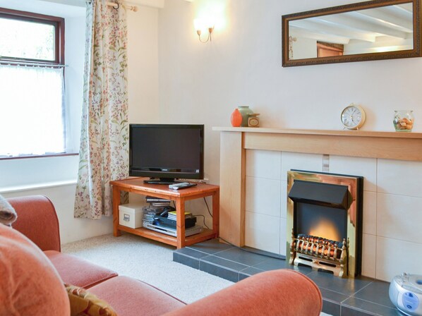 A living room with a fireplace, a television on a wooden stand, and a sofa.
