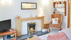 Una sala de estar con chimenea, televisor, sofá y sillón.