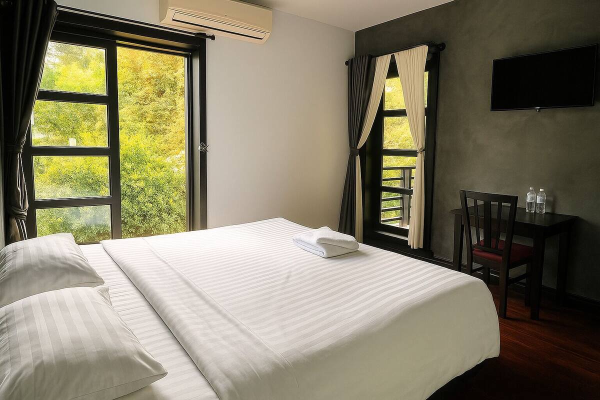 A hotel room with a bed, a desk, and a TV.