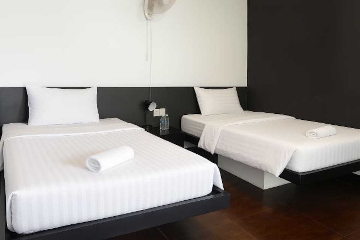 A hotel room with two beds, each with white bedding and a rolled towel.