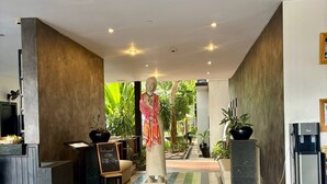 Un hall de hotel con mostrador de recepción, una estatua y un dispensador de agua.