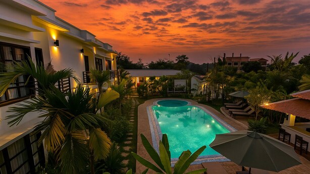 Una piscina rodeada de exuberante vegetación y edificios modernos, con un cielo al atardecer de fondo.