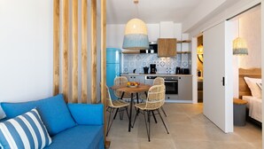 Una cocina moderna con zona de comedor, que incluye un sofá azul, sillas de mimbre y un frutero sobre la mesa.