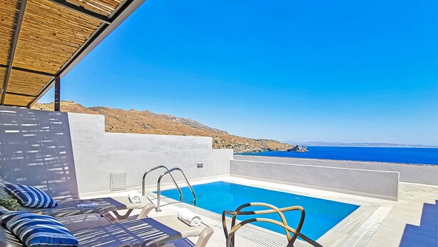 Un área junto a la piscina con sillones de descanso, una piscina pequeña y vistas al mar.