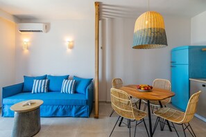 A modern living room with a blue sofa, wicker chairs, a wooden dining table with fruit, and a blue refrigerator. - Varkotopi villa 2,Pool,Near the Beach,South Crete (Rethymno)