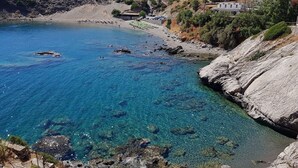 Una zona costera con aguas azul turquesa, terreno rocoso y algunos edificios.