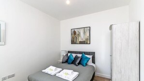 Ein modernes Schlafzimmer mit Bett, Kissen, einem Gemälde und einem Kleiderschrank.