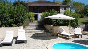 A villa with a swimming pool, outdoor seating, and a staircase leading to the entrance.