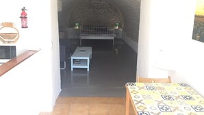A room with a stone wall, a bed, a small table, and a fire extinguisher.