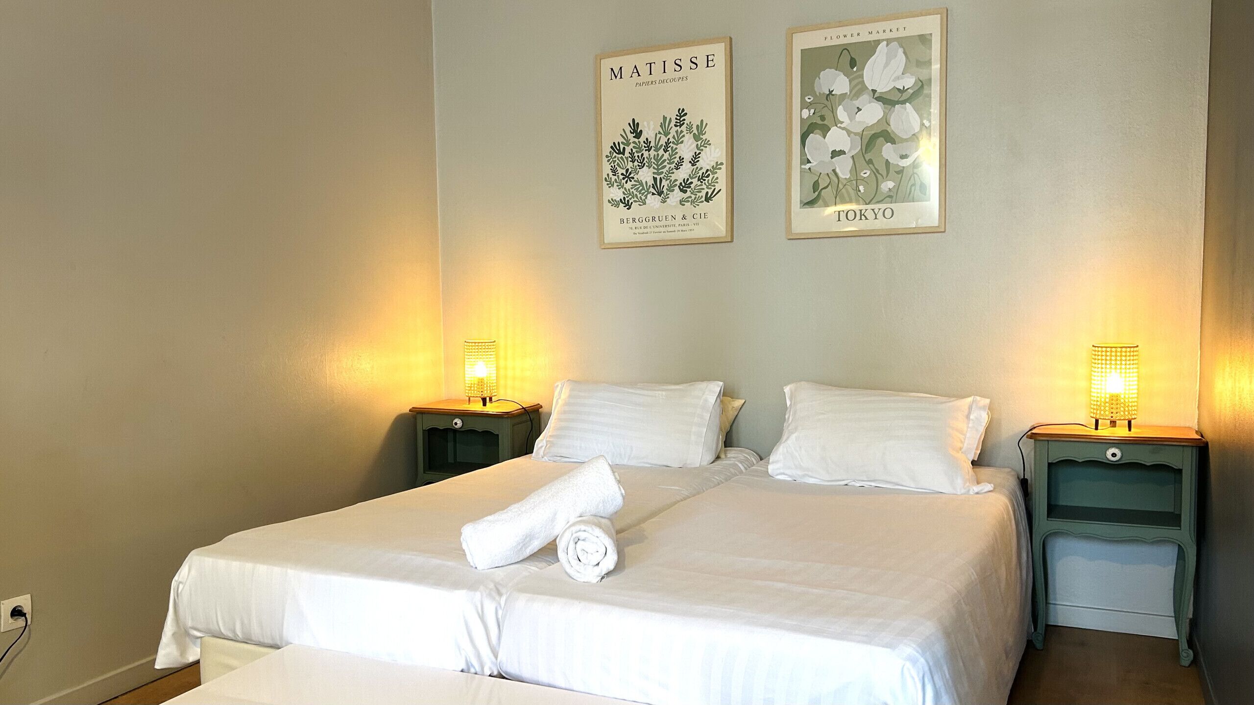 A hotel room with a large bed, two bedside tables, and two wall-mounted lamps.