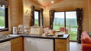 A wooden cabin kitchen with a sink, coffee maker, and dish rack.