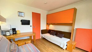 A compact room with a bed, a sofa, a small table with a coffee maker, and a TV on the wall. - Studio for 2 at slopes, pets allowed (Les Menuires)