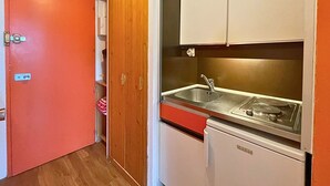 A compact kitchen with a sink, a refrigerator, and wooden cabinets. - Studio for 2 at slopes, pets allowed (Les Menuires)