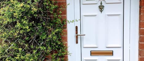 A white front door with a brass knocker, a mail slot, and a small window above the door.