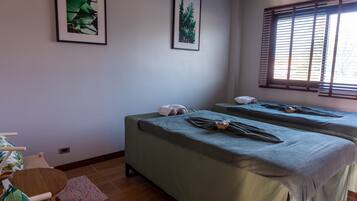 Two single beds, each with a bedspread, are positioned in this room, accompanied by framed prints and a small table with a chair.