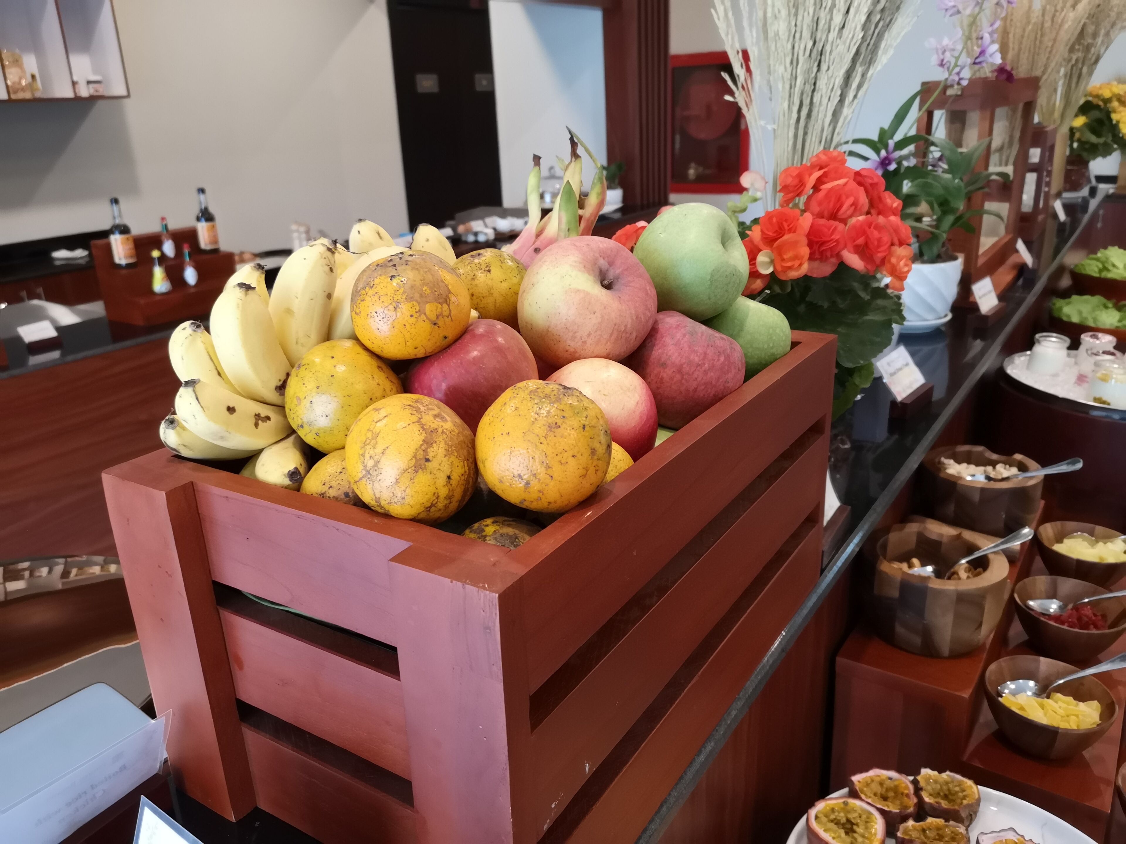 A fruit display with bananas, apples, and oranges in a wooden crate.