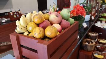 A fruit display with bananas, apples, and oranges in a wooden crate.