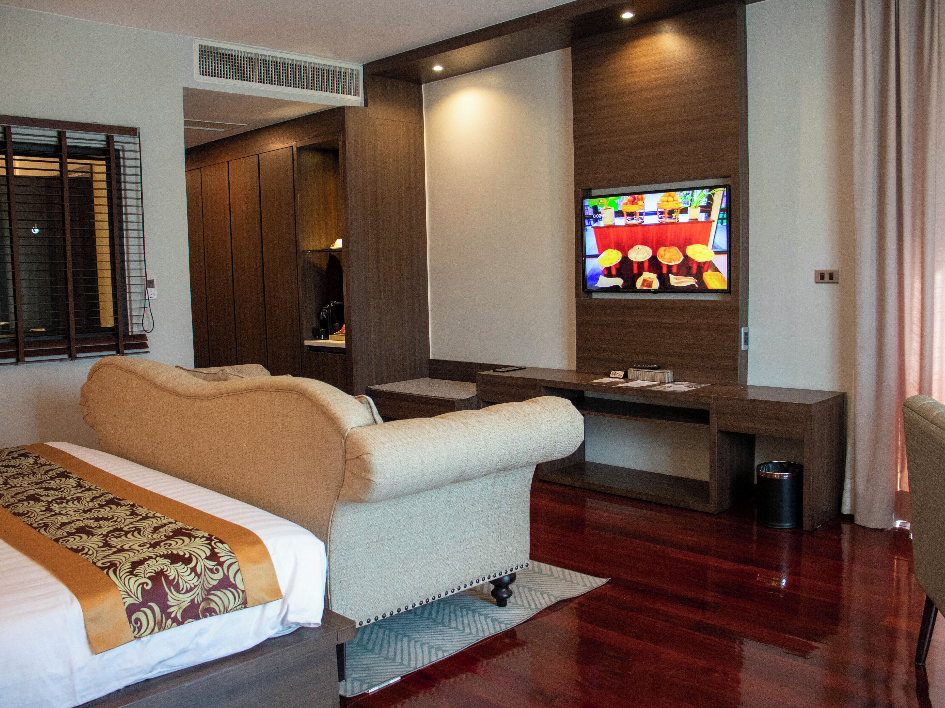 A hotel room with a bed, a desk, a TV, and a trash bin.